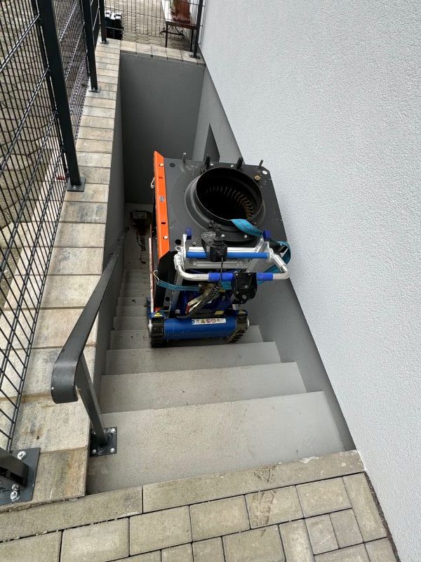 Inneneinheit einer Heizungsanlage, die über eine Außentreppe in den Keller eines hauses befördert wird